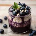 Delicious blueberry overnight oats in a jar topped with fresh blueberries.